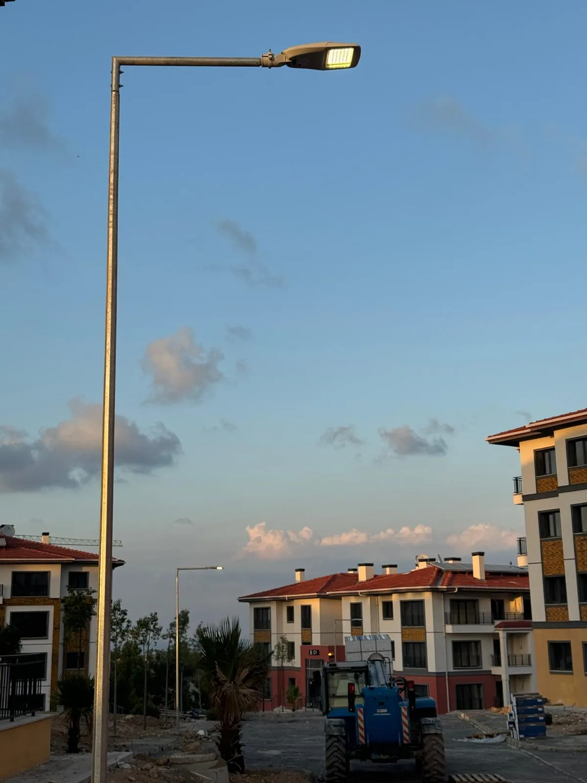 Alacakaranlıkta konutlar arasında yanan aydınlatma direği